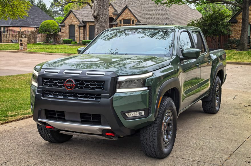 A Tactical Green 2026 Nissan Frontier Pro-4X parked on a rocky mountain outcrop overlooking a vast mountain range.